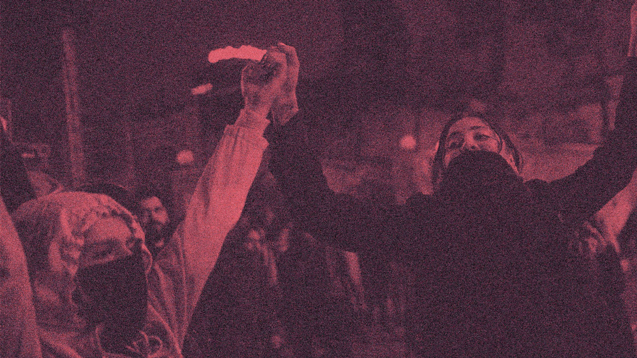 Two women holding hands in the air at a protest.