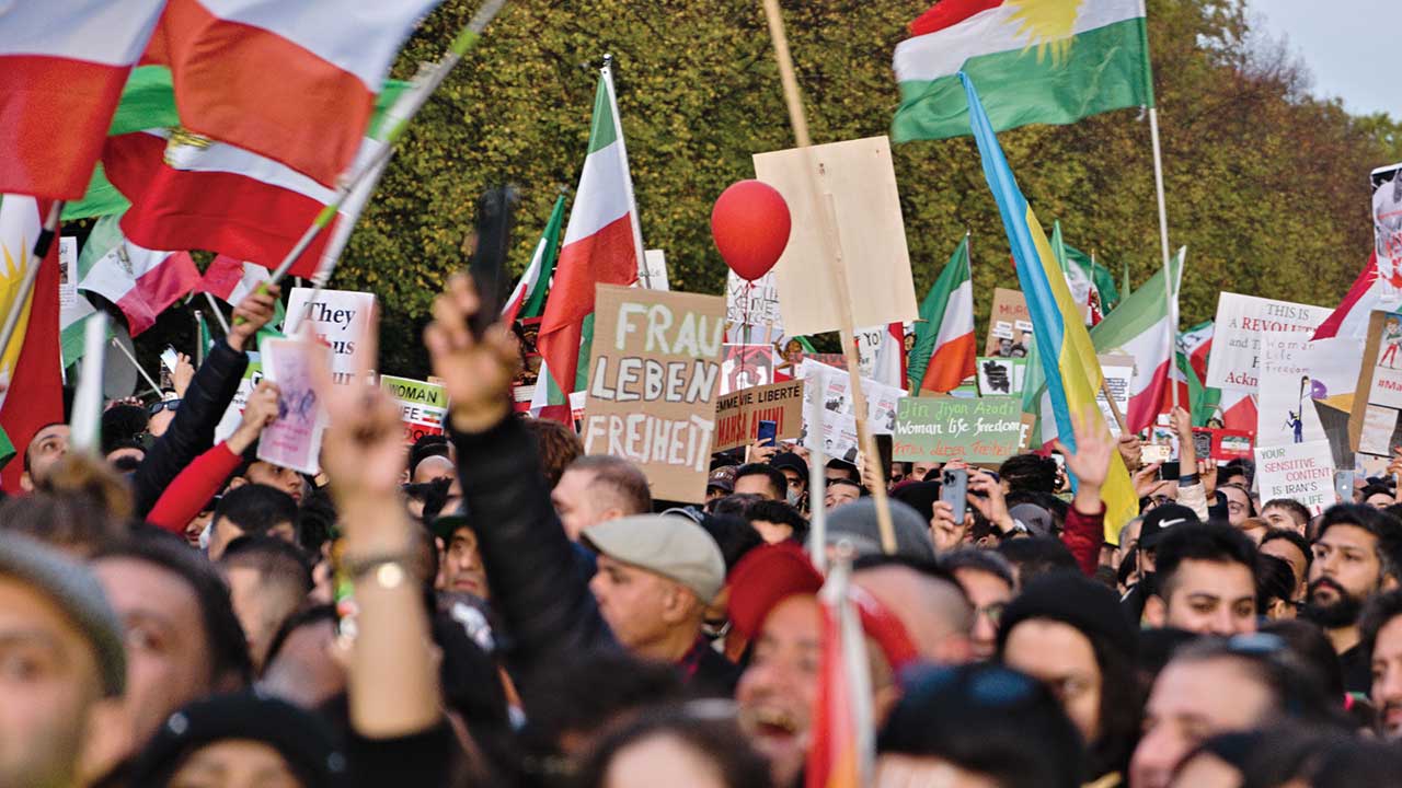 Crowd of people holding signs at a solidarity demonstration in Berlin related to Mahsa Amini protests in Iran.