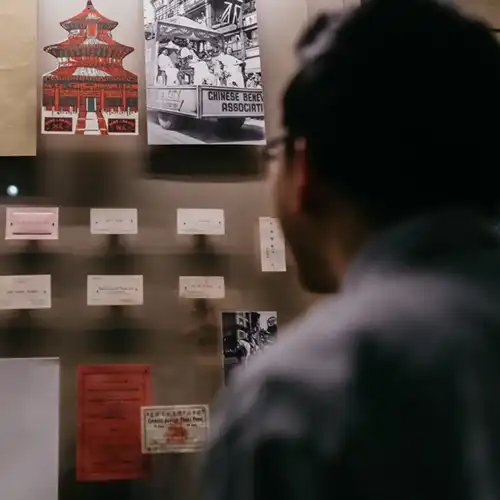A man looking at a gallery exhibit of early Chinese migration.